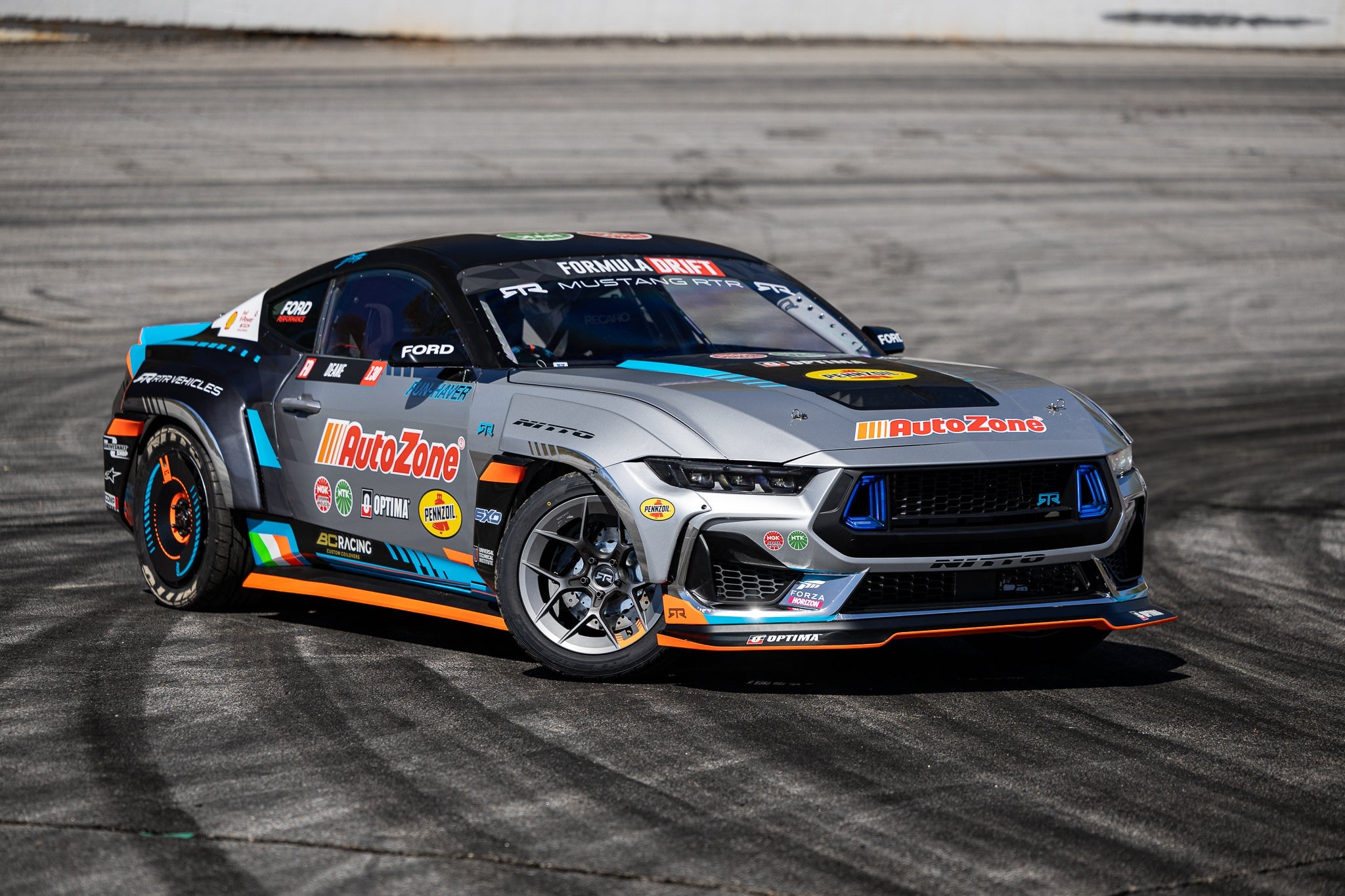 James Deane's 2024 Mustang RTR Spec 5 on a track, showcasing a close-up of partner logos. Motorsport and performance car elements visible.