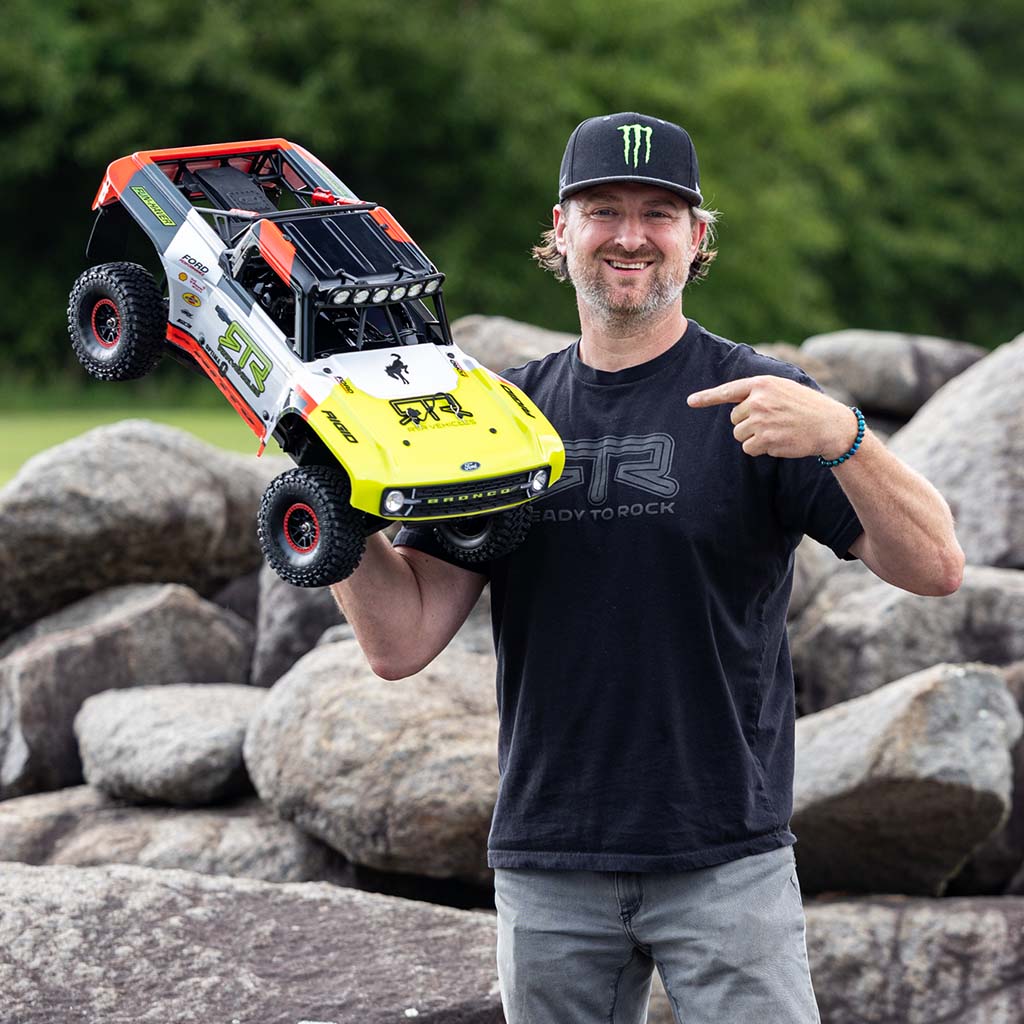Vaughn Gittin Jr holding a remote-controlled car in front of a rocky background