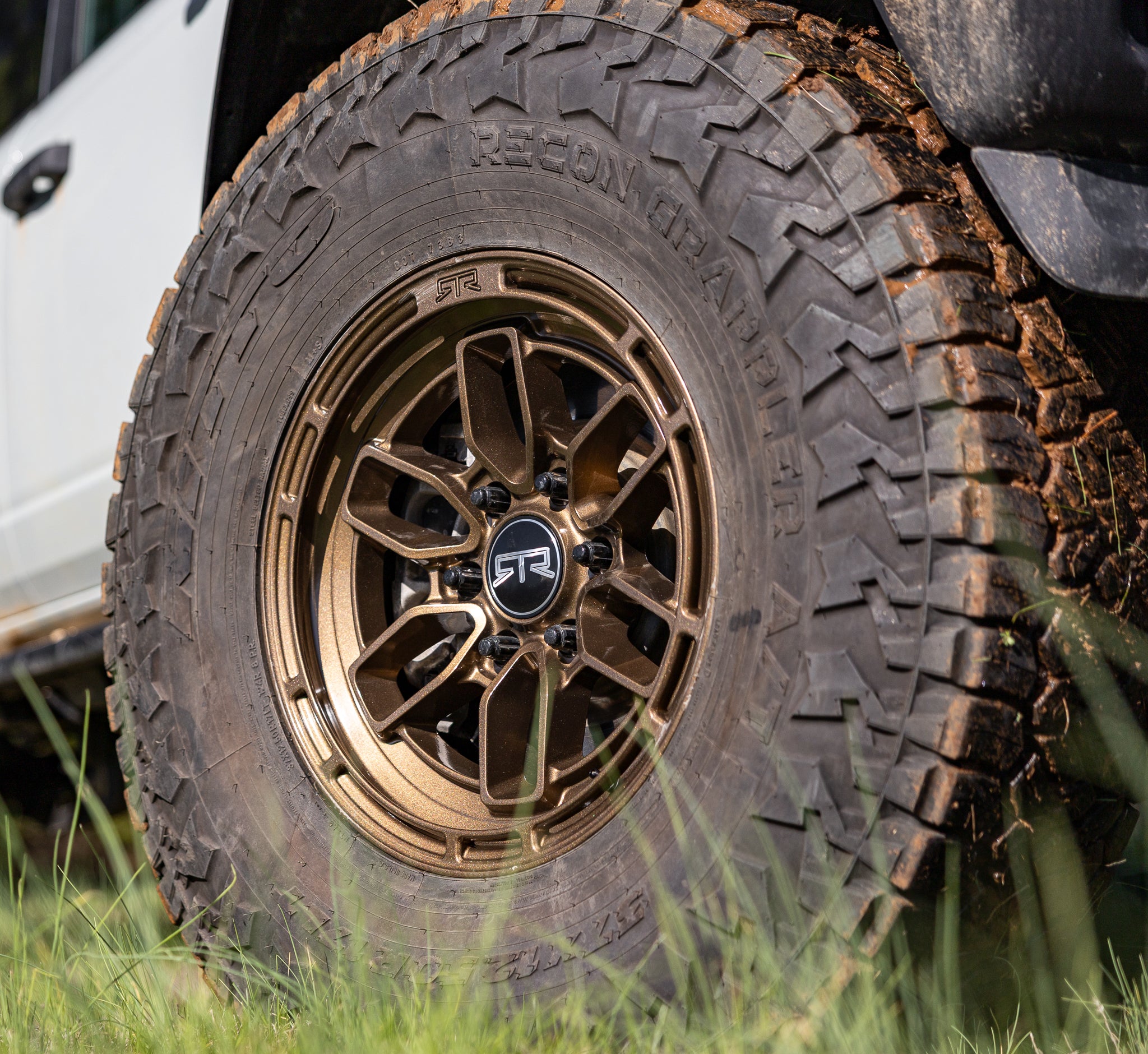 Close-up of a rugged tire with a bronze RTR Evo 6 on a Bronco in a grassy area