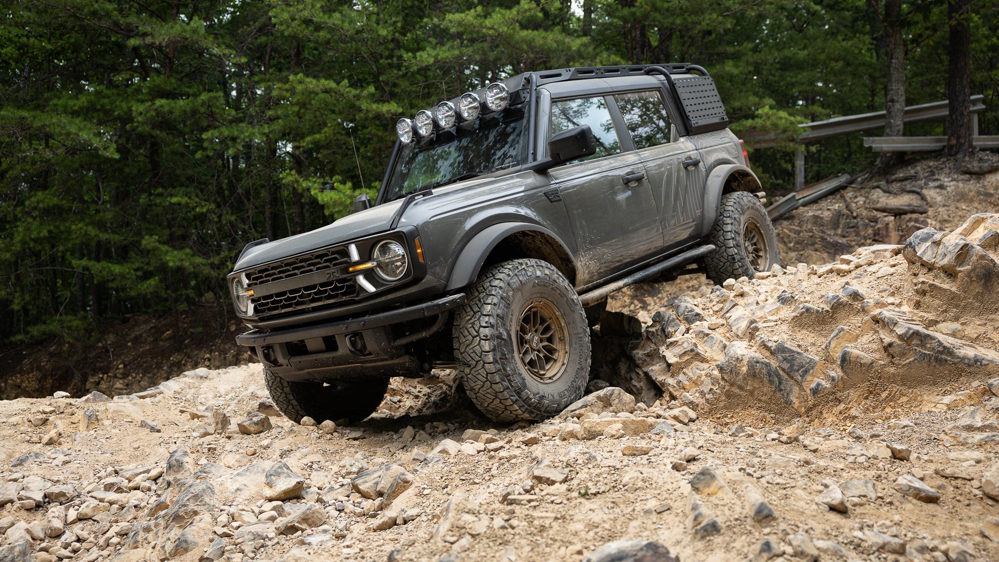 A Bronco RTR ROVR navigating a rocky terrain with trees in the background