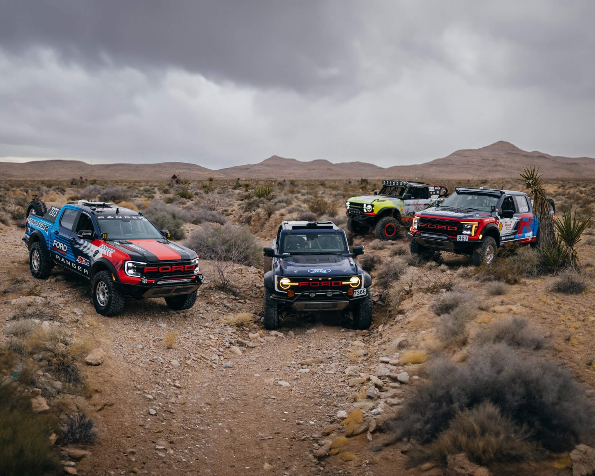 The RTR Vehicles Off-Road fleet, including the Ford Bronco Raptor, F-150 Raptor R, and Ranger Raptor, stands together in the desert, symbolizing Ford Performance’s off-road dominance.