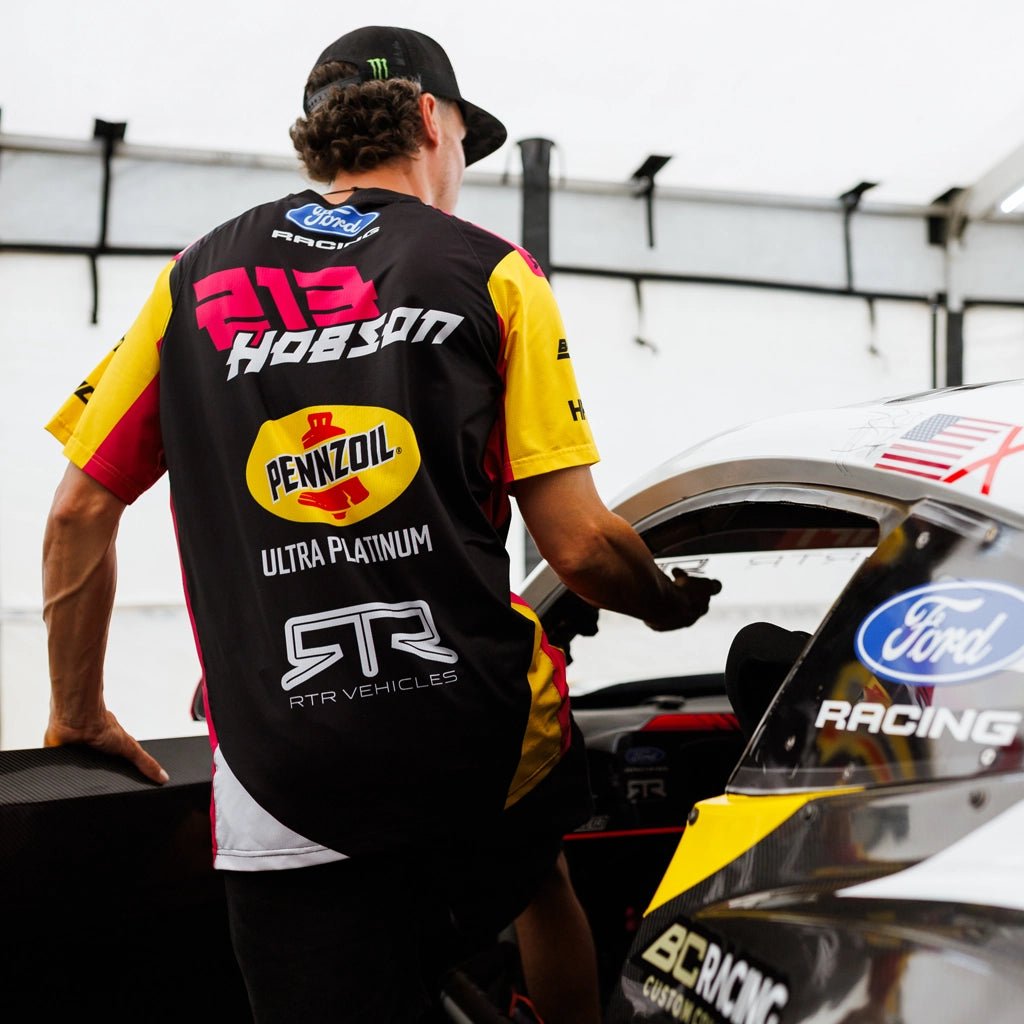 Ben Hobson wearing his 2026 RTR Drift Team Sublimated Shirt getting into his Ford Mustang RTR Spec 5 competition car at Formula Drift.
