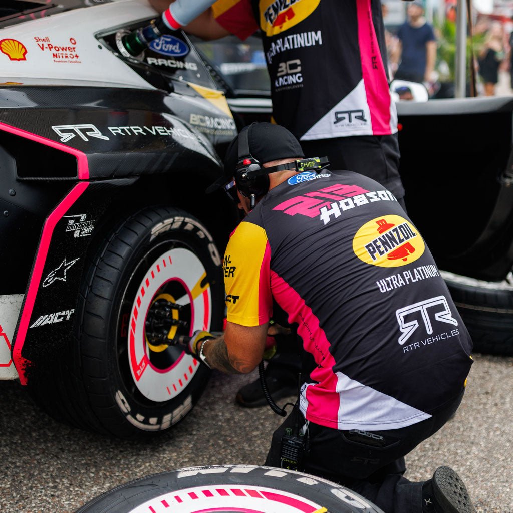 RTR Vehicles crew members wearing Ben Hobson 2026 RTR Drift Team Sublimated Shirts changing tires on Ben Hobson's Ford Mustang RTR at a Formula Drift event.