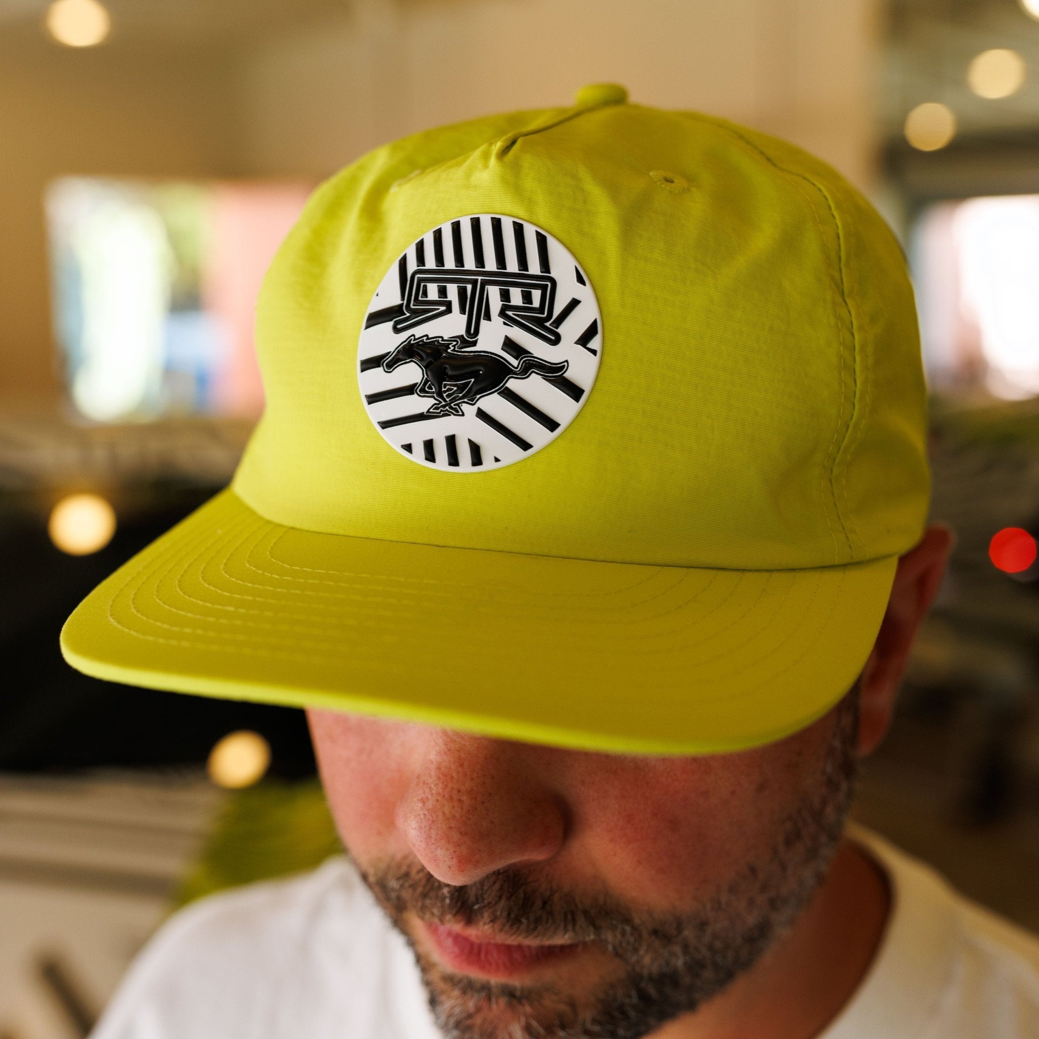Man wearing Ford Mustang x RTR Collection 5 Panel Unstructured Snapback Hat in neon-lime with RTR x Mustang emblem, styled in a five-panel design.
