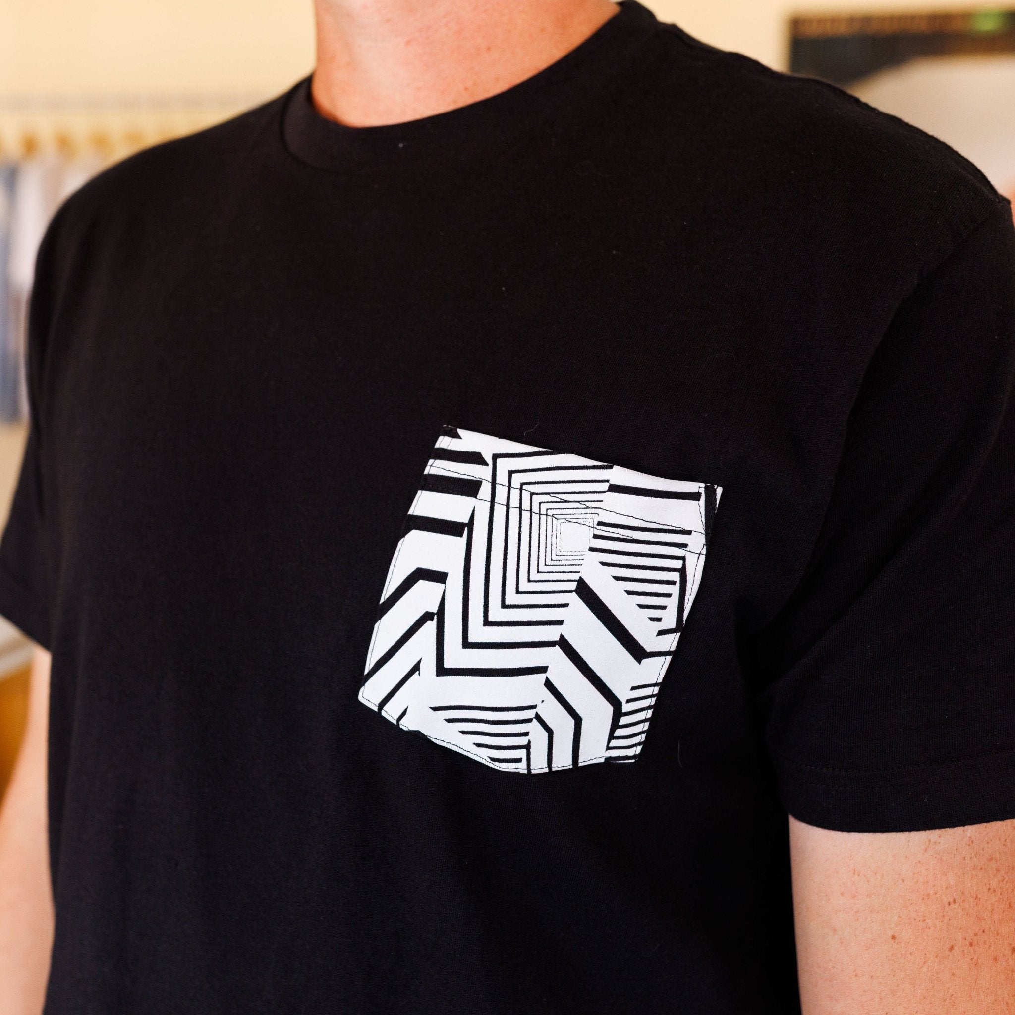 Person wearing the Ford Mustang x RTR Collection Pocket T-Shirt featuring a geometric-patterned pocket, reflecting the RTR’s dazzle camo design on a plain black background.