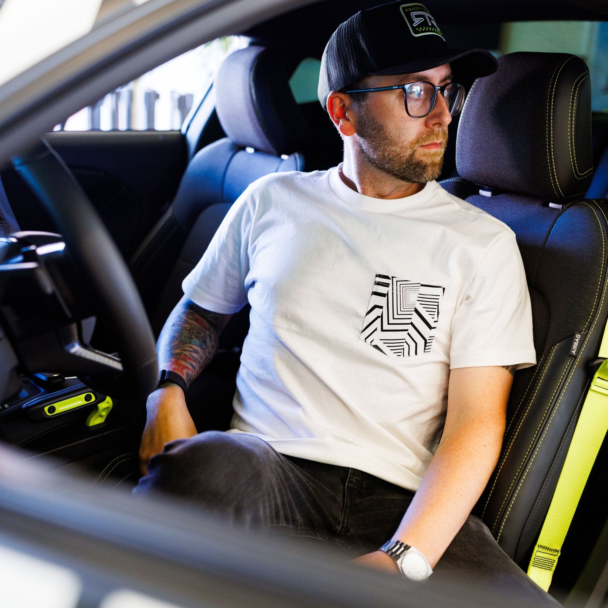 Man in a car wears the Ford Mustang x RTR Collection Pocket T-Shirt, featuring a black-and-white geometric pocket design, embodying performance and style.