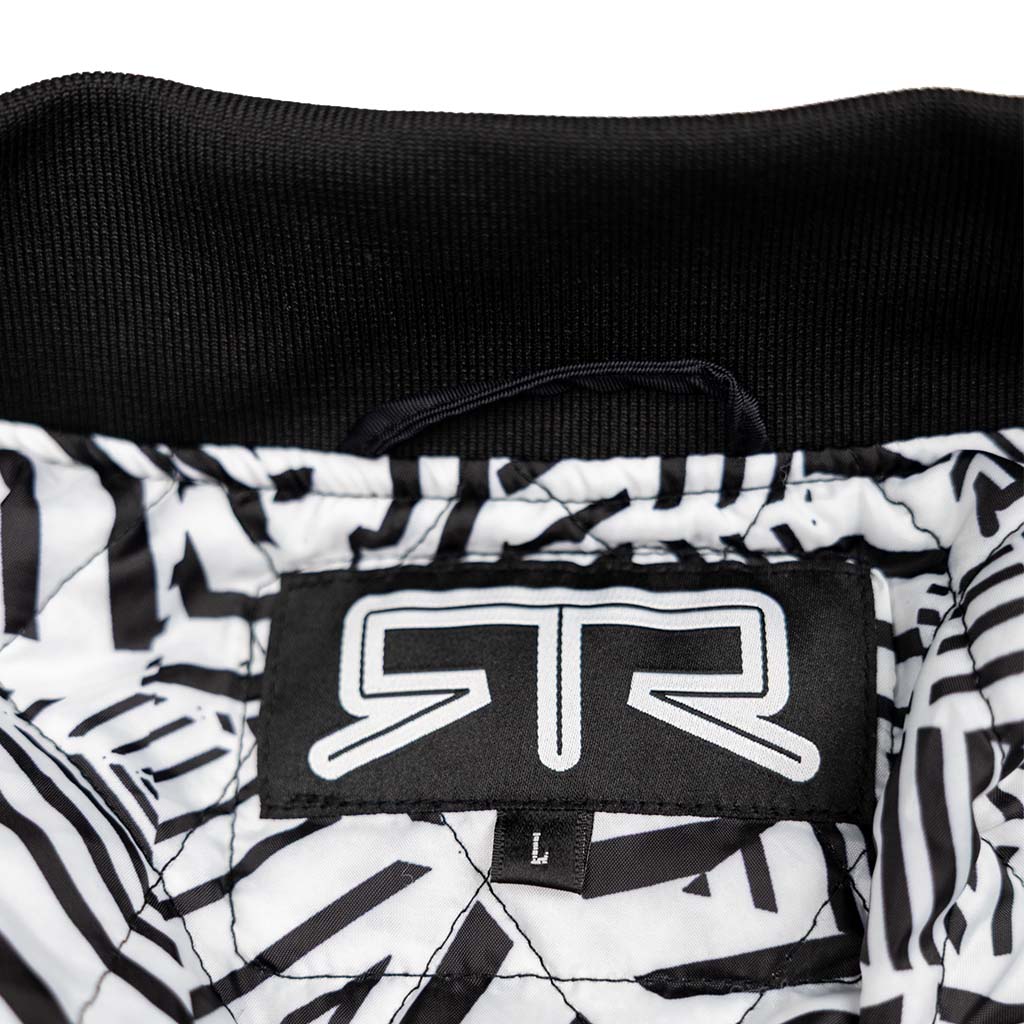 Close-up of the Ford Mustang x RTR Collection Stealth Jacket collar, featuring a black fabric, woven RR label, size L tab, and dazzle camo lining.