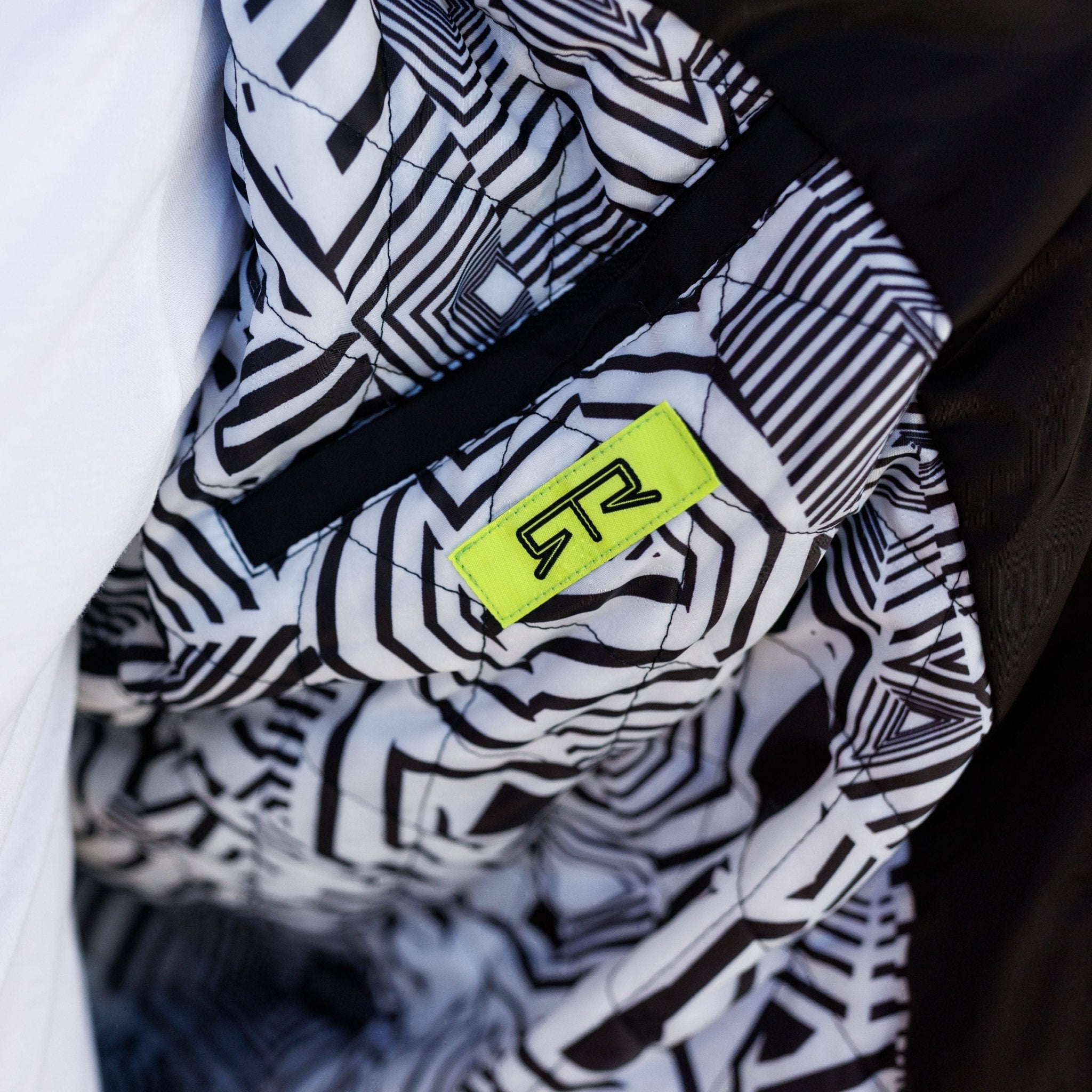 Close-up of Ford Mustang x RTR Collection Stealth Jacket’s interior, showing quilted black-and-white geometric lining with RTR logo, hinting at innovative performance design.