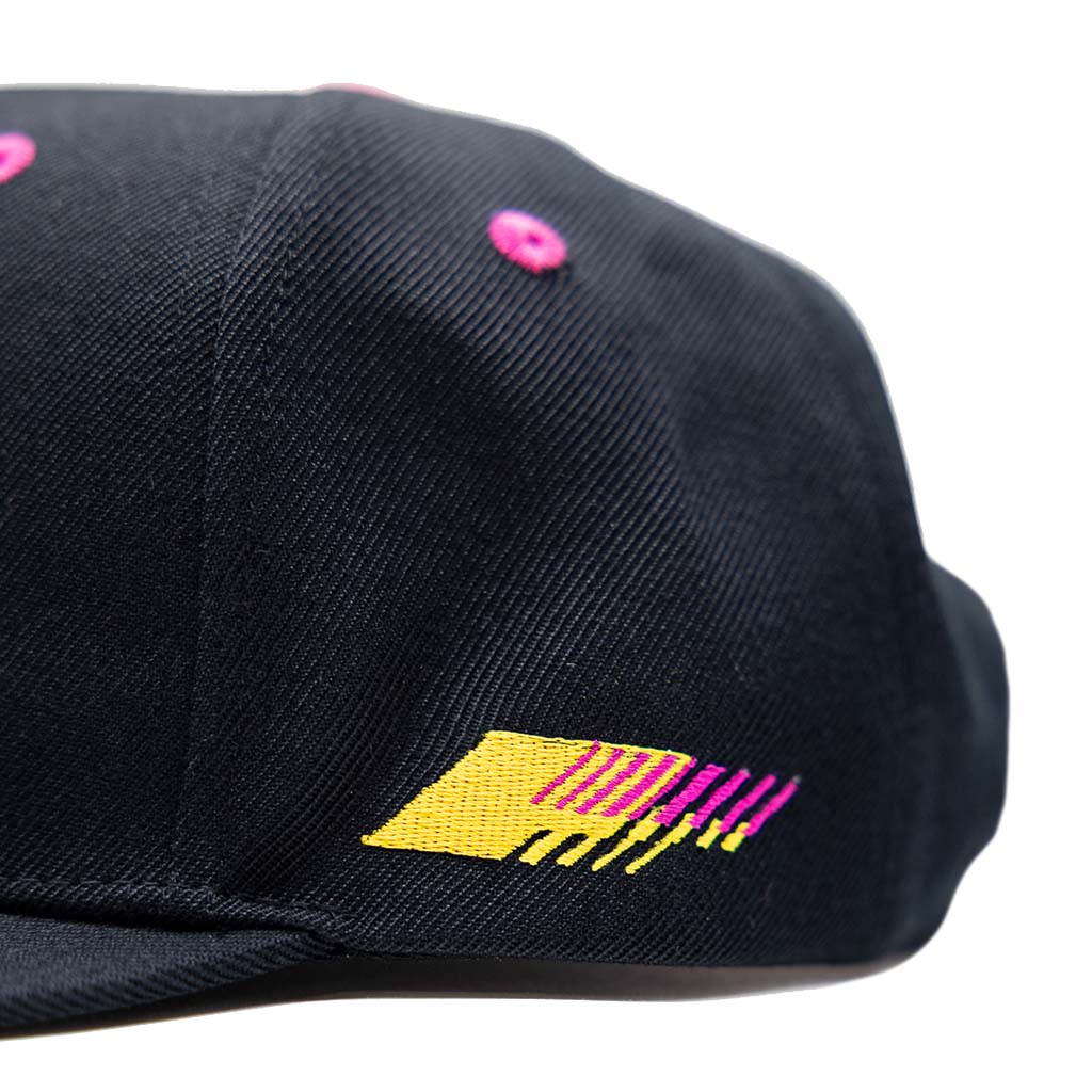 Black RTR Drift Team Snapback featuring pink and yellow design, structured crown, flat brim, and embroidered logo, inspired by motorsports drivers' cars and personalities.