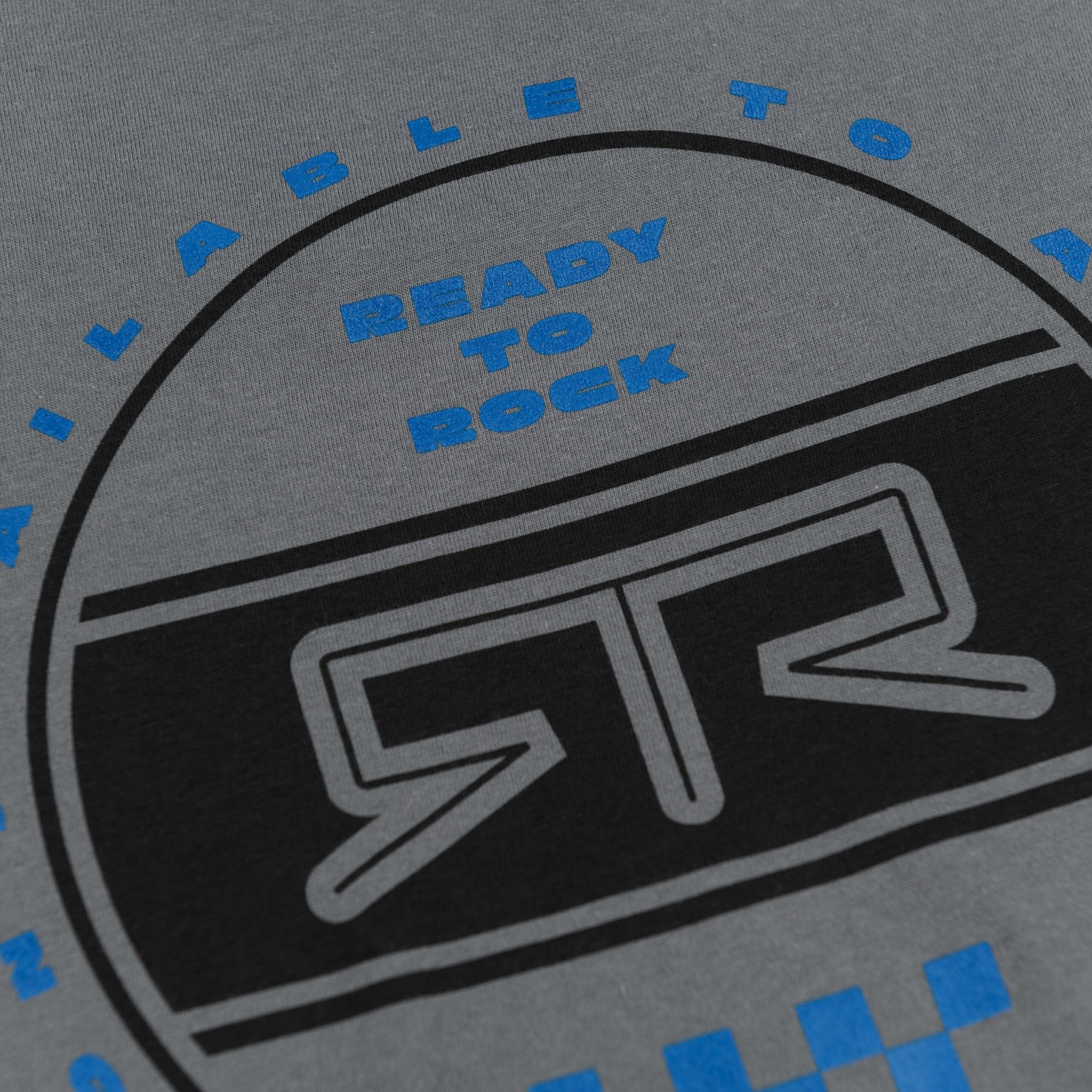 RTR Heritage Badge T-Shirt close-up showing a blue logo on grey knitted fabric, symbolizing RTR ethos with a bold graphic design.