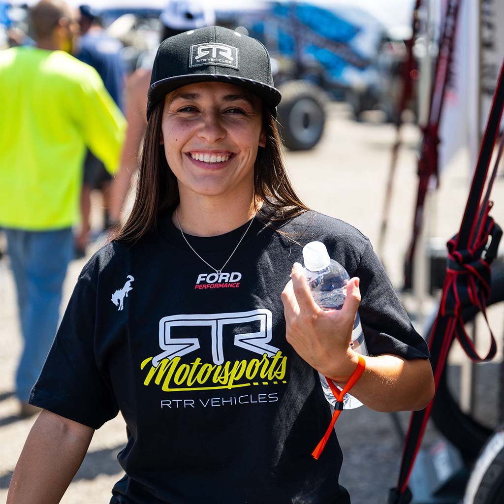 Person wearing a black 'Ford Performance' and 'RTR Motorsports' shirt, holding a water bottle.