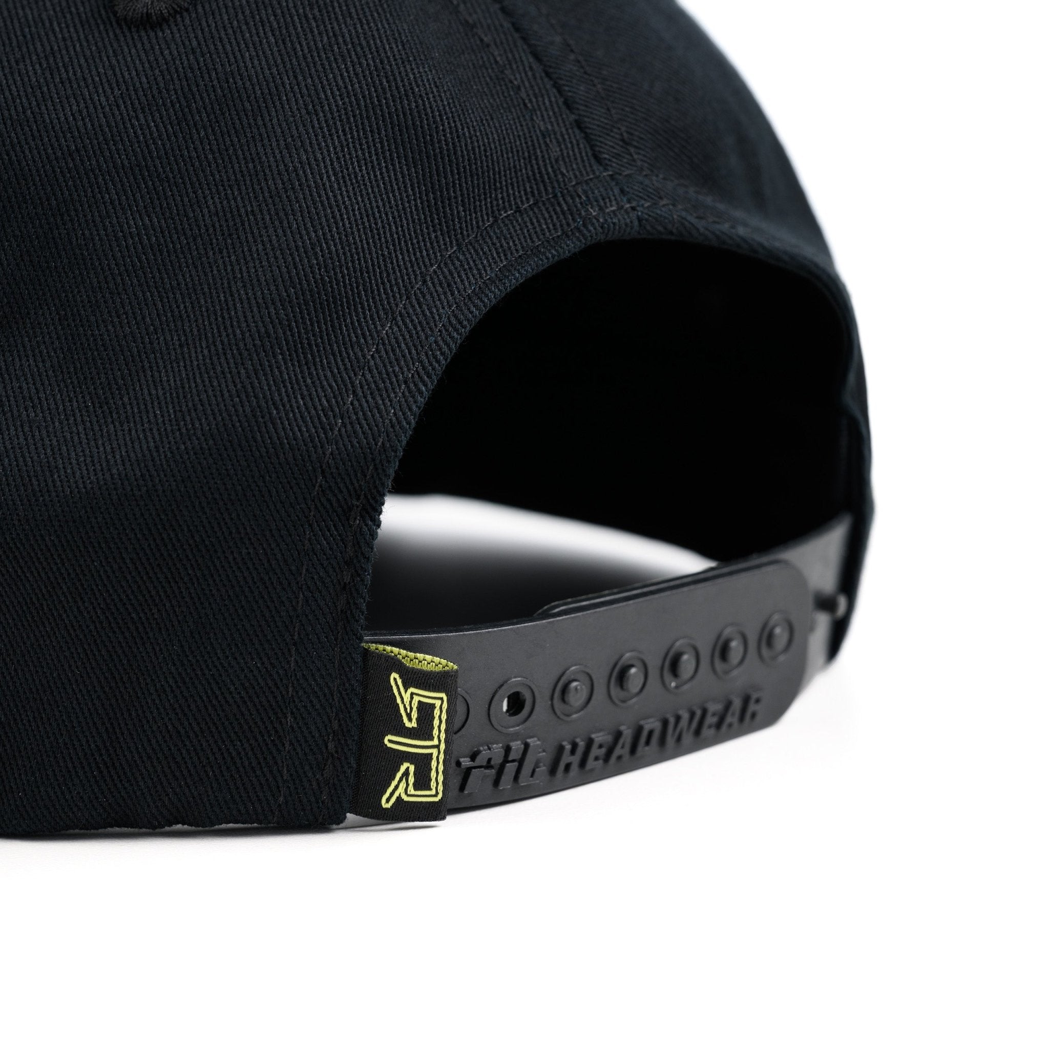 Close-up of a black cap with a RTR® logo on the strap against a white background