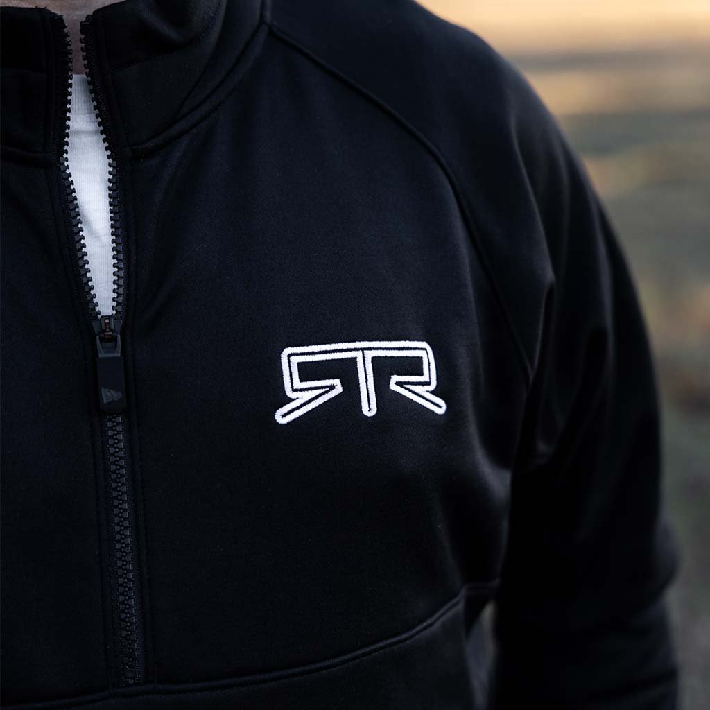 Person wearing RTR Quarter Zip Pullover with raglan sleeves, zipper pockets, and quarter zipper, showcasing the embroidered RTR logo on the chest.