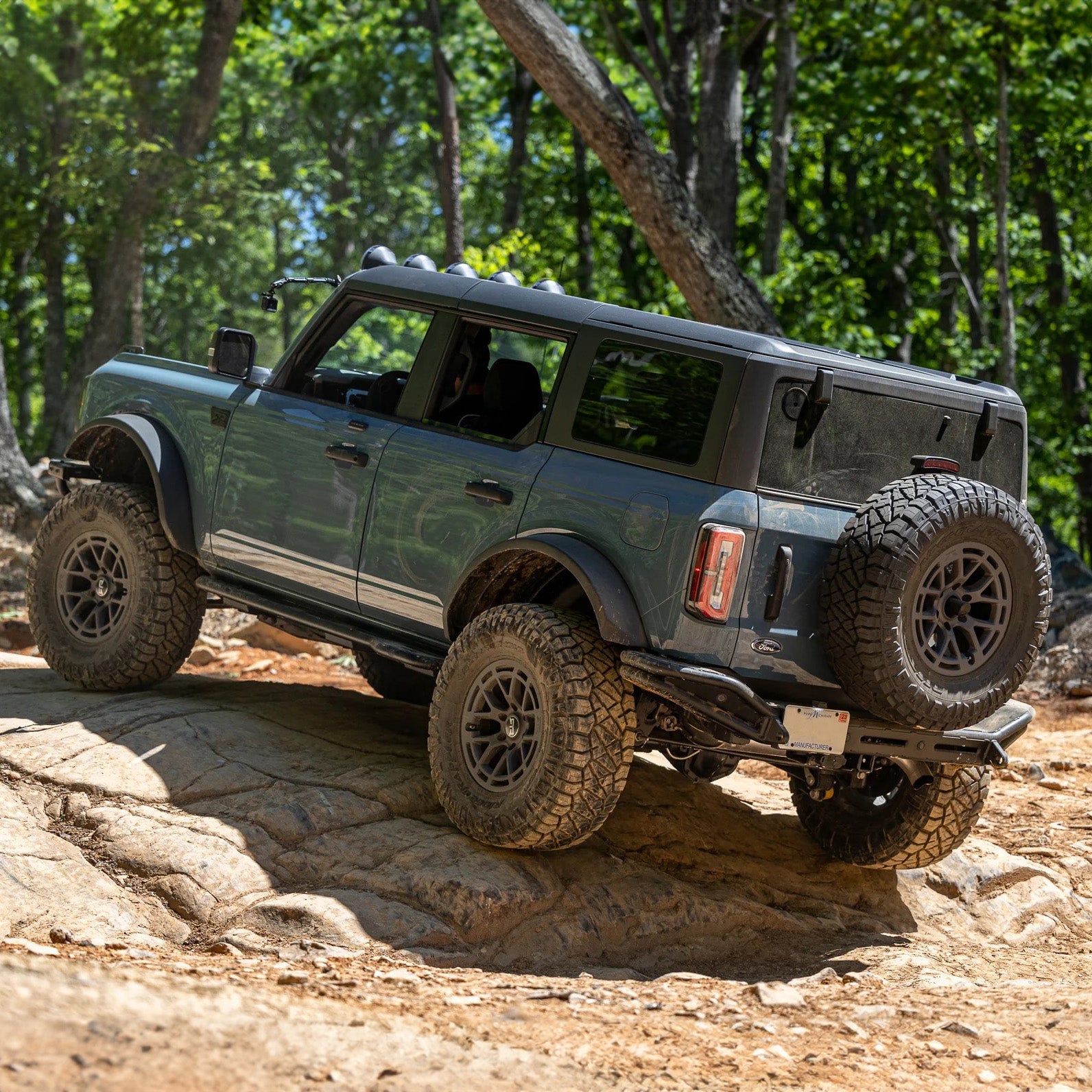 Ford Bronco on a rock ledge, showcasing the RTR Trail Protection Bundle with rock sliders, rear bumper, and front bumper end caps for enhanced off-road capability.