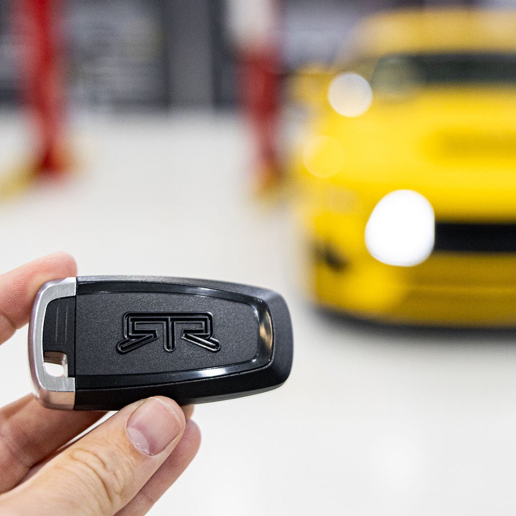 A hand holds an RTR Keyfob Backplate with embossed logo, designed for Ford enthusiasts. Made of ABS plastic, ready for custom paint to match your vehicle.