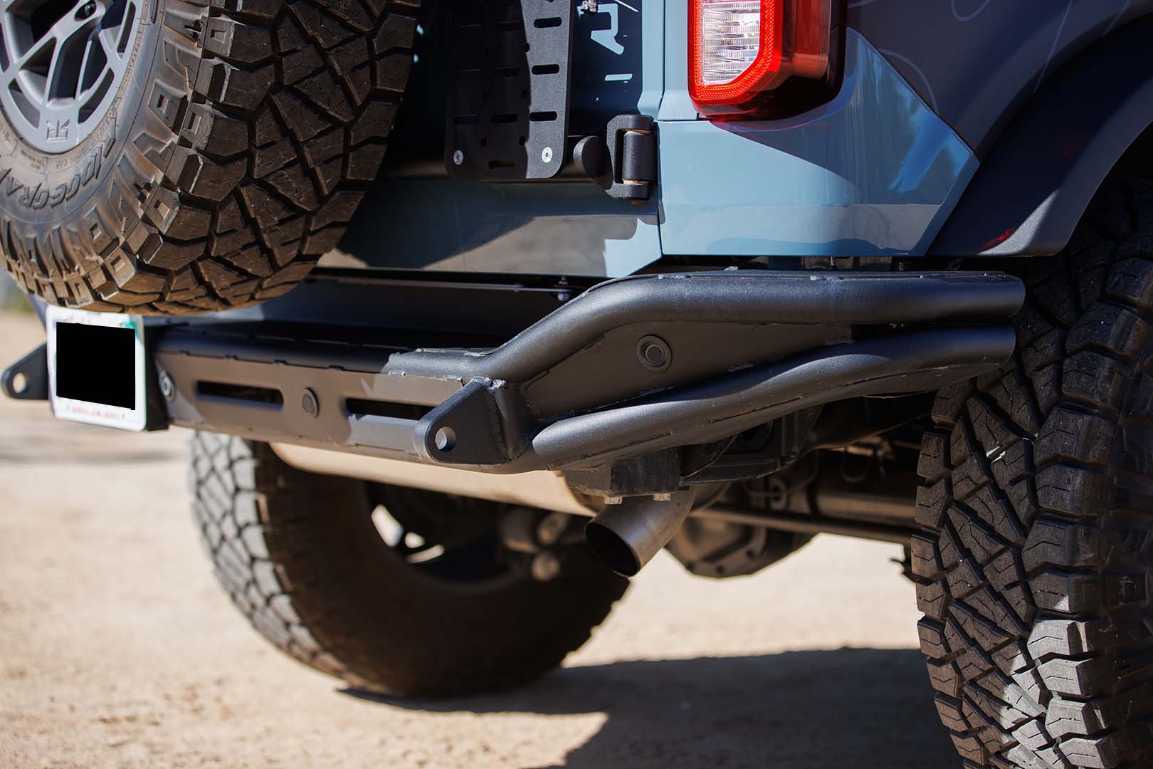 Bronco Trail Safe Package showing a close-up of a tire with rugged tread, bumper, and rock sliders designed for off-road performance and durability.