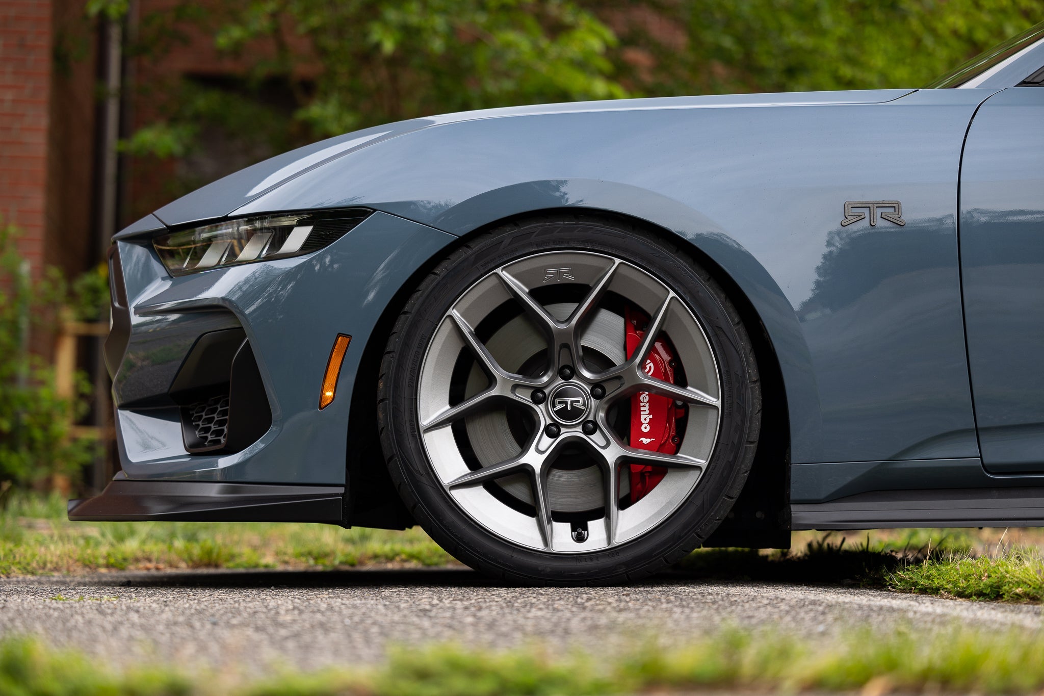 Close-up of RTR Tactical Performance Lowering Springs on a Mustang wheel with red brake caliper, enhancing handling and appearance with a sleek muscle car stance.