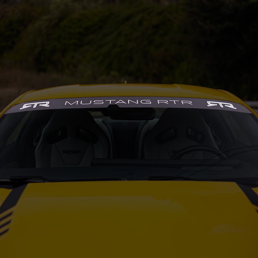 Front view of a yellow car showcasing the RTR S650 Starter Pack, including the RTR backplate, license plate frame, pedal covers, shift knob, and windshield banner.