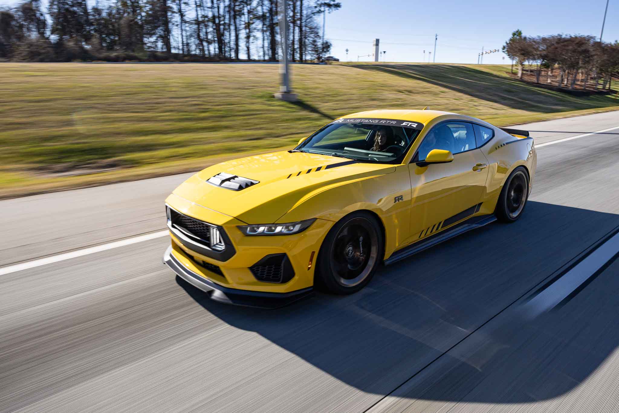 A 2024 Mustang RTR Spec 2 in Yellow Splash drives down the road