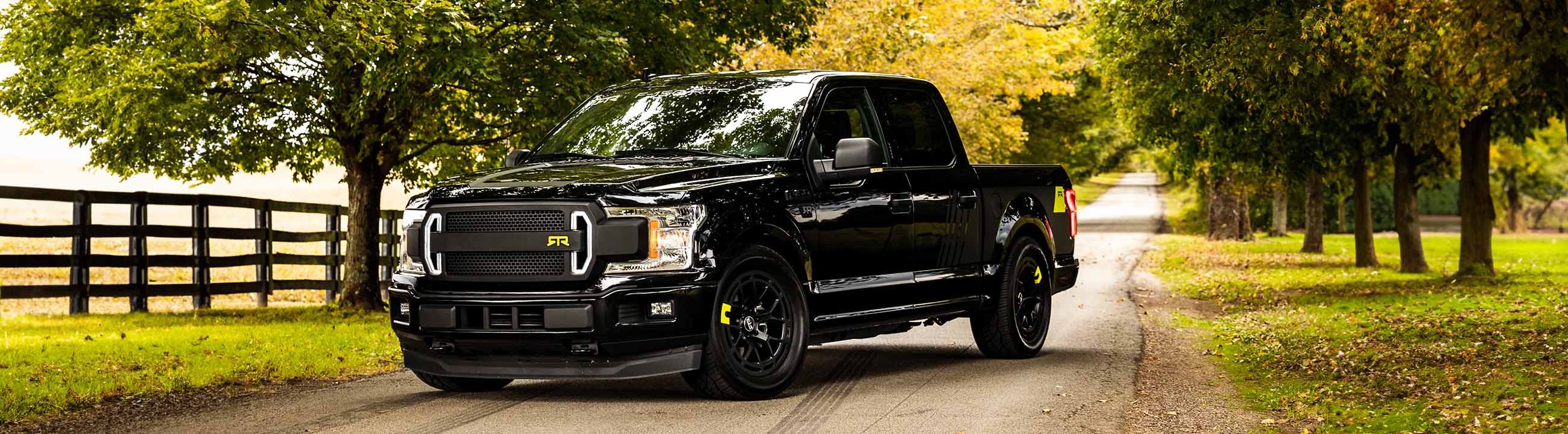 A black Ford F-150 RTR parked on a road, showcasing RTR parts and accessories for Ford F-150s