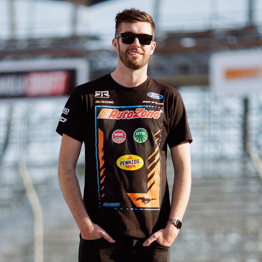 Jame Deane in a black shirt with logos, wearing sunglasses, waering the 2024 James Deane Official RTR Drift Team Shirt. Limited-edition tee celebrating Formula Drift Pro champion James The Machine Deane.