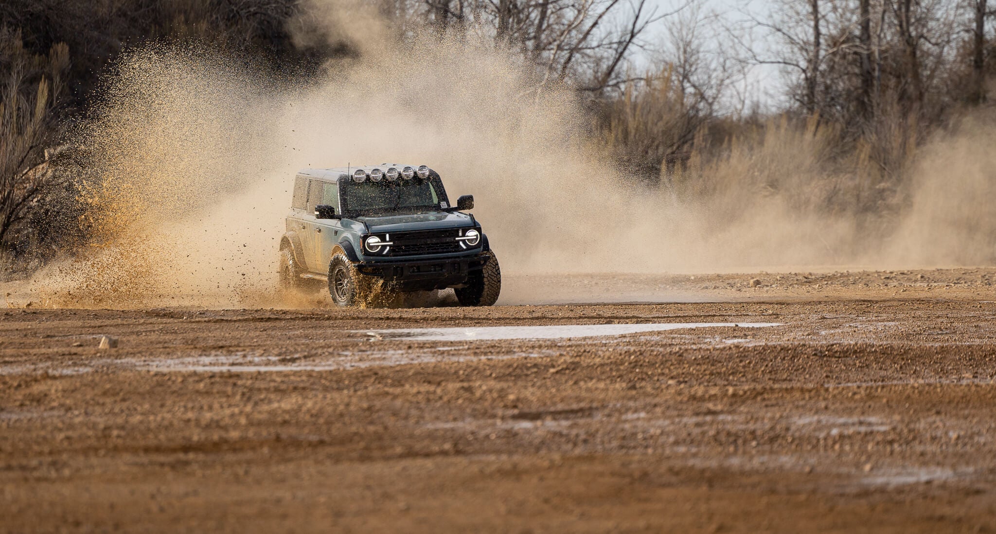 The 2024 Bronco RTR drives through mud and dirt in an offroad park