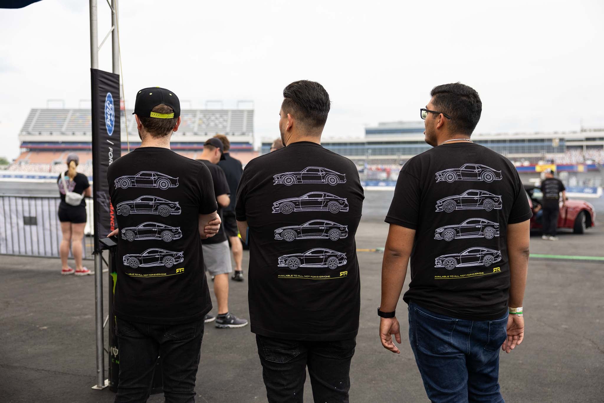 Three men watch the drifting demos at Charlotte Motor Speedway