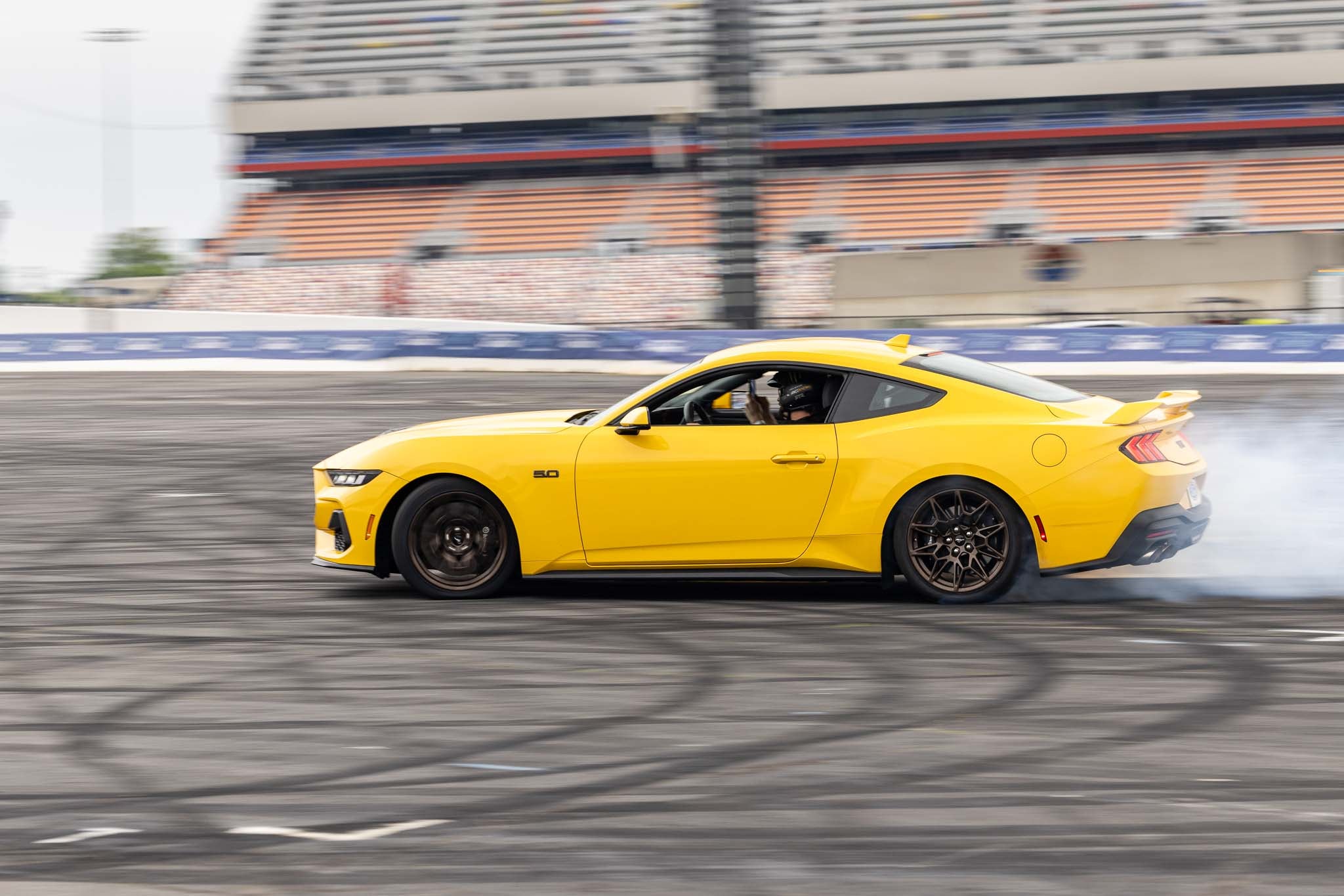 A yellow 2024 Mustang drifts at Charlotte Motor Speedway