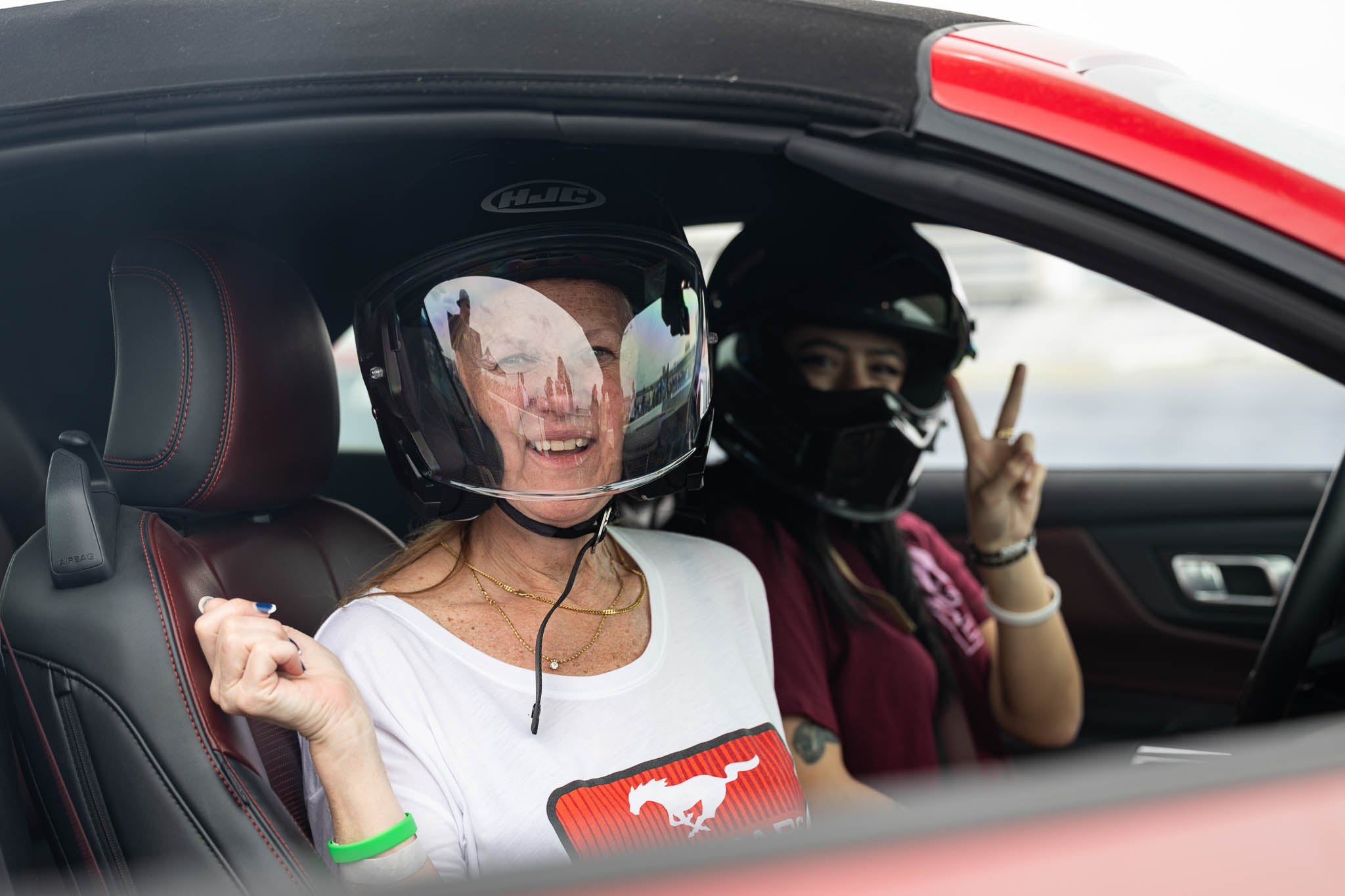 Two women smile for the camera as they enjoy a ride in a 2024 Mustang