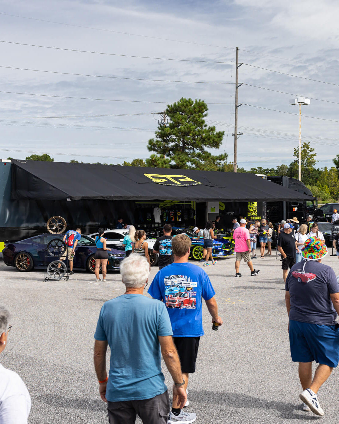 Car show or gathering with people and cars in an open area.