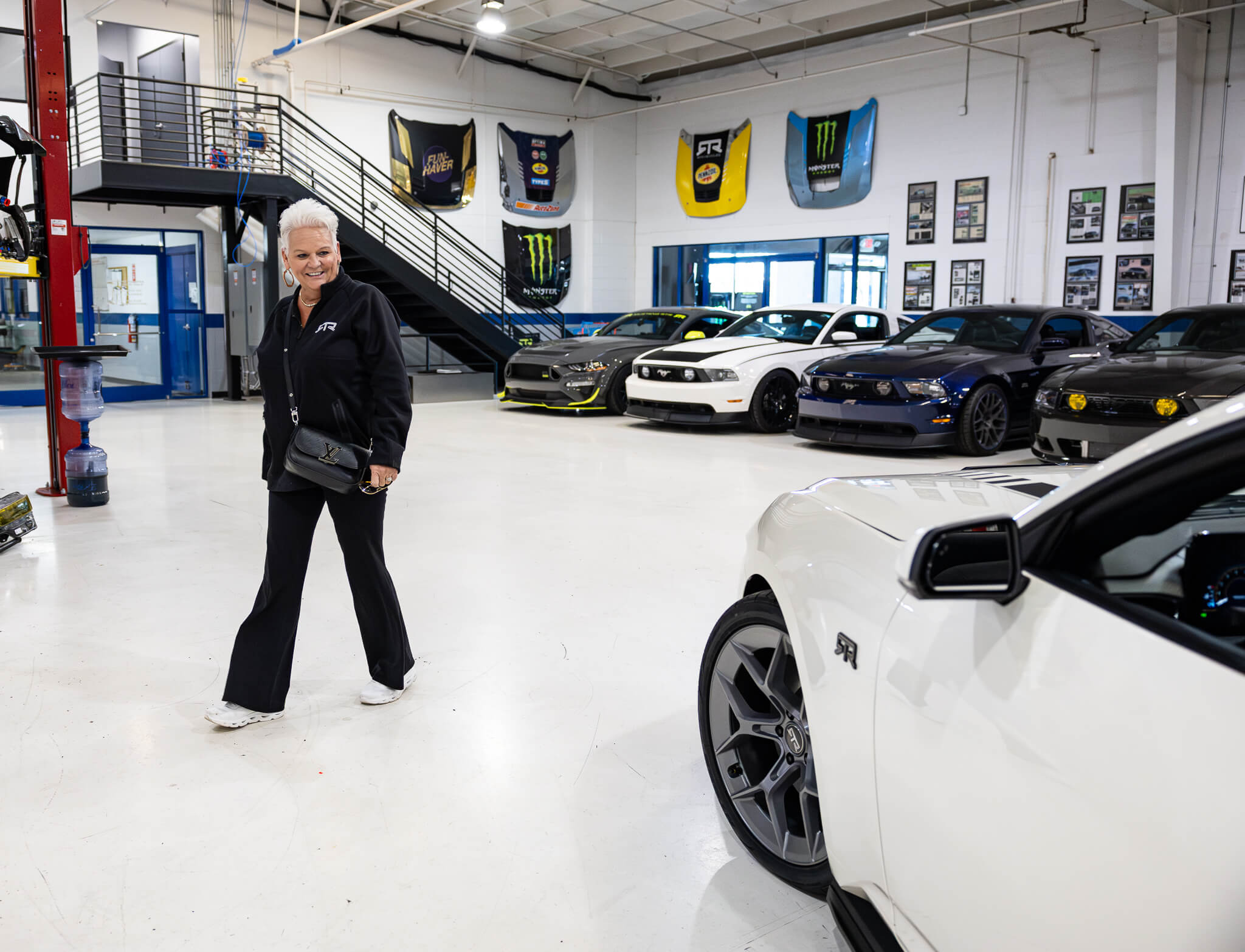 A woman looks at the 2025 Wimbledon white 60th anniversary Mustang RTR inside the RTR shop