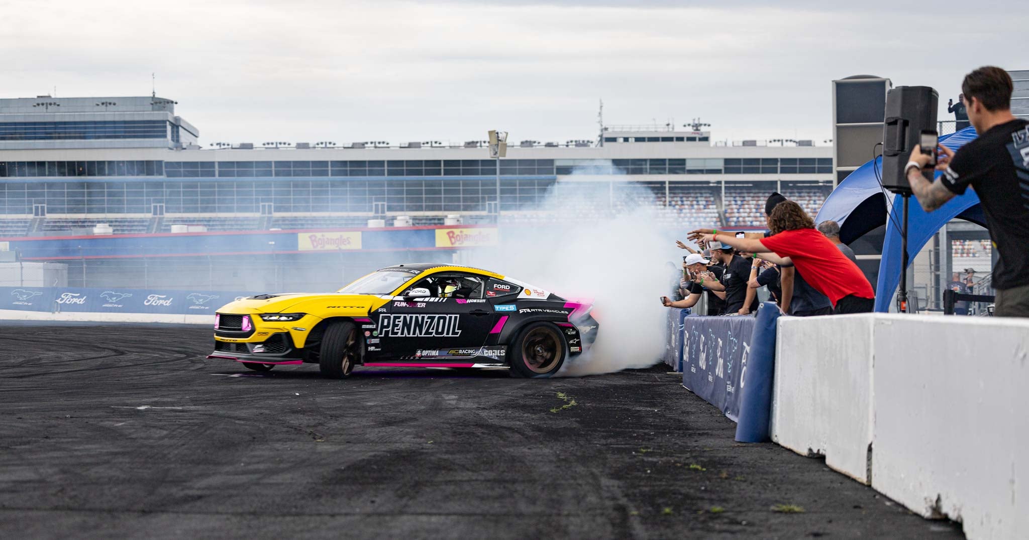 Ben Hobson drifts next to a wall as a crowd cheers him on at Charlotte Motor Speedway