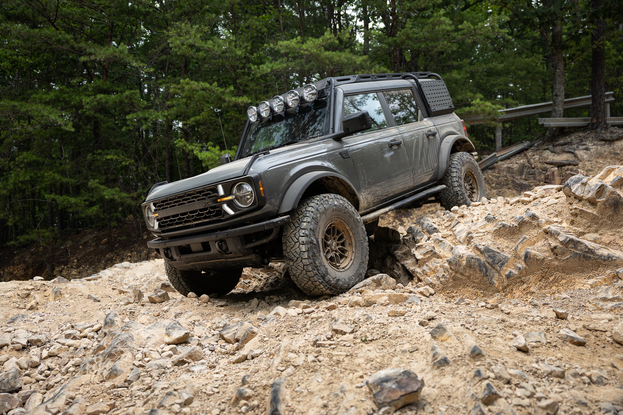 A Bronco RTR ROVR navigating a rocky terrain with trees in the background