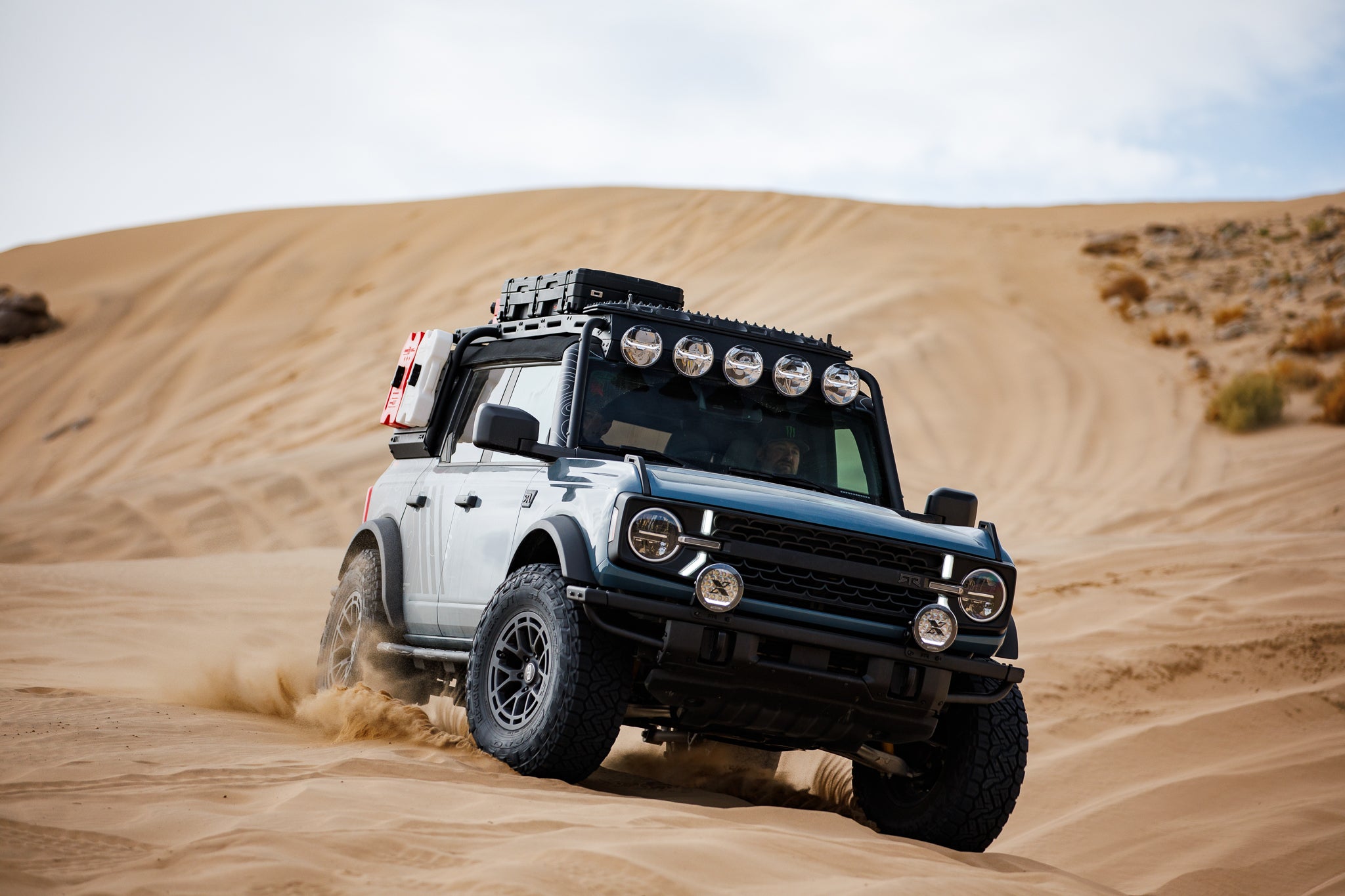 A 2024 Bronco RTR ROVR drives over a sand dune in the desert