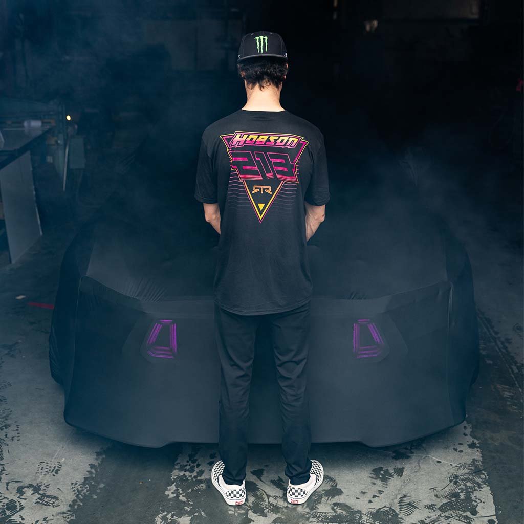 Ben Hobson in a black shirt with a green Monster energy logo on a black hat stands in front of a covered 2024 Mustang, showcasing the limited edition Ben Hobson X RTR Tee.