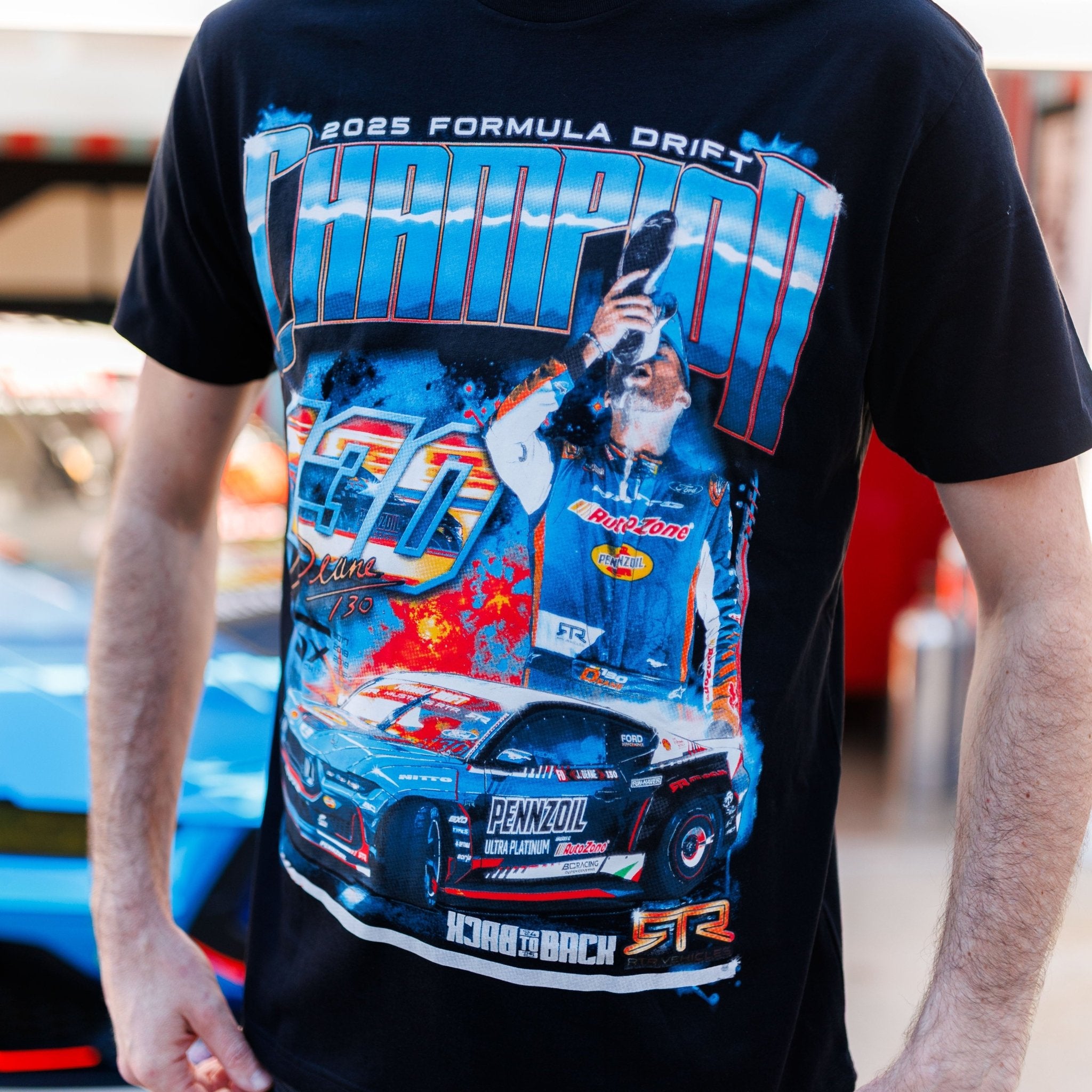 James Deane 2025 Championship T-Shirt featuring a colorful graphic of car #70, a driver with trophy, Champion and Back-to-Back text.