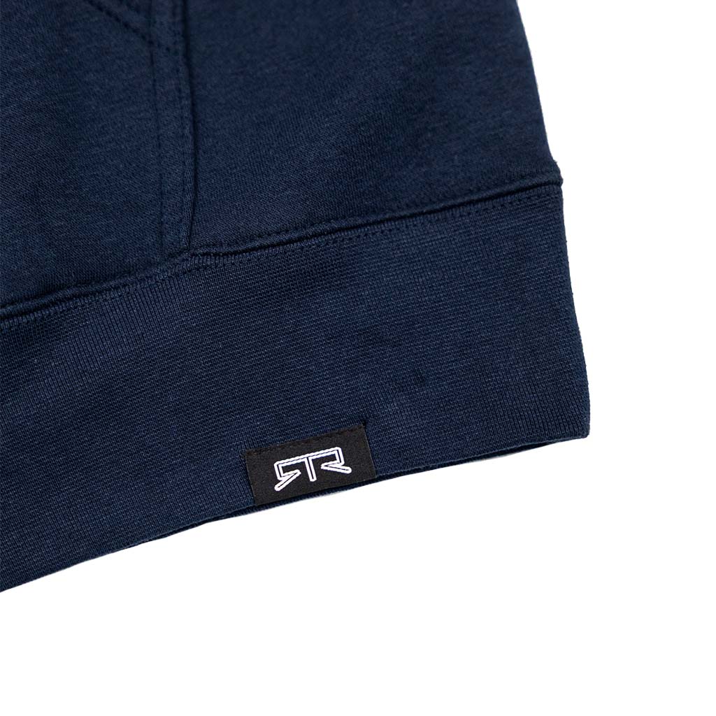 Navy-blue Loren Healy Flat Out Hoodie close-up showing ribbed hem, kangaroo pocket stitching, and black label with white RR logo, reflecting off-road racing inspiration.