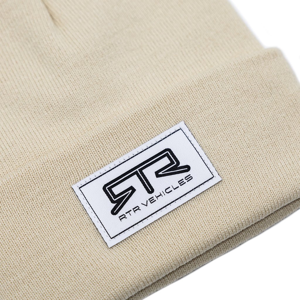 Tan RTR Beanie featuring a stitched white and black RTR logo label, designed for comfort and versatility, ideal for embracing the RTR lifestyle with functionality and style.