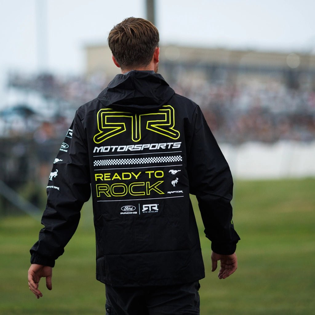 Back view of an RTR Team crew member wearing the Black and Hyperlime RTR Motorsports Windbreaker Waterproof Jacket at Formula Drift.