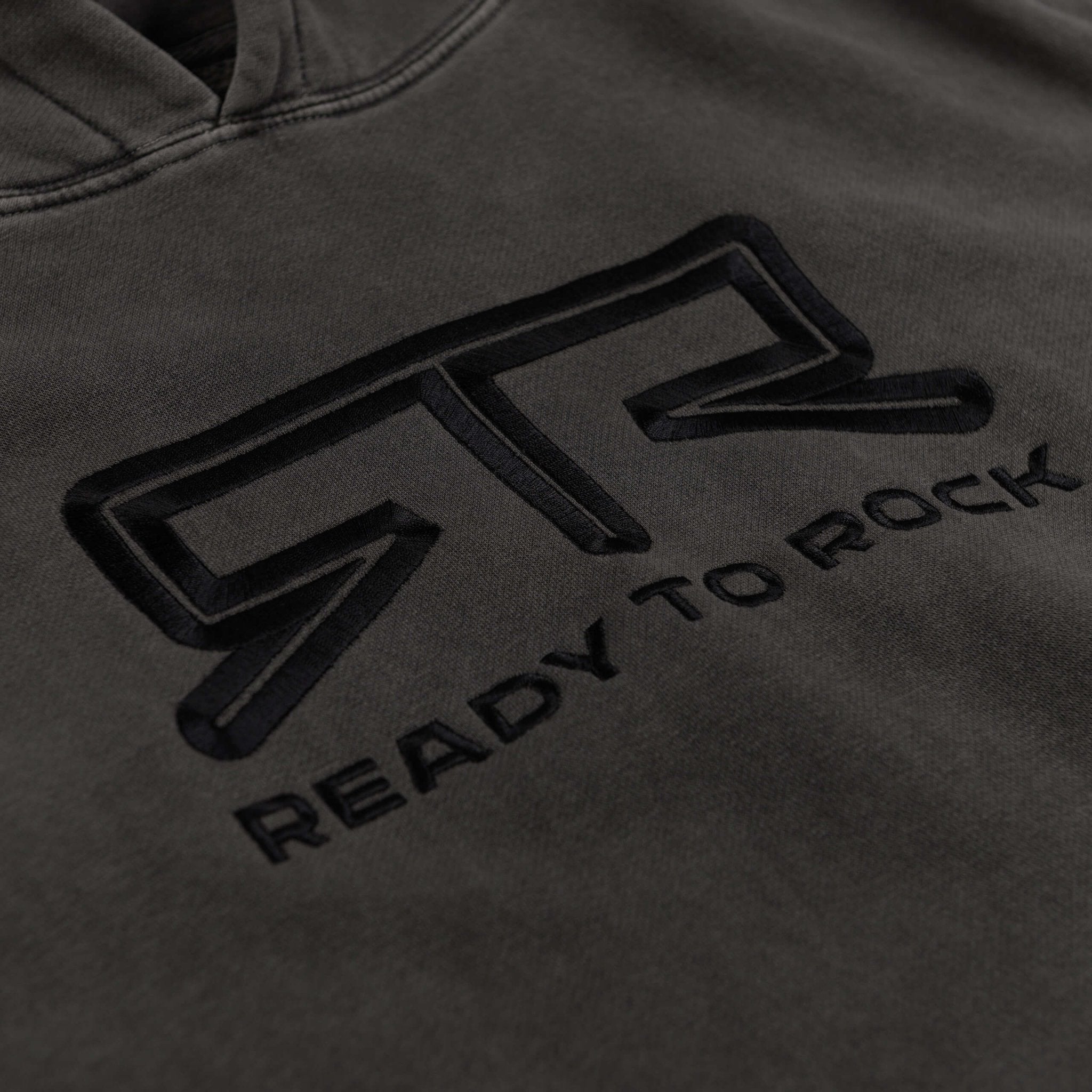 Close-up of the RTR Tonal Logo Hoodie featuring raised tonal logo embroidery on heavyweight fleece, highlighting its unique pigment black wash