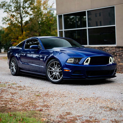 Deep-blue Ford Mustang with RTR Upper Grille featuring Signature LED Accent Lighting, showcasing its aggressive design and enhanced airflow on a gravel driveway.
