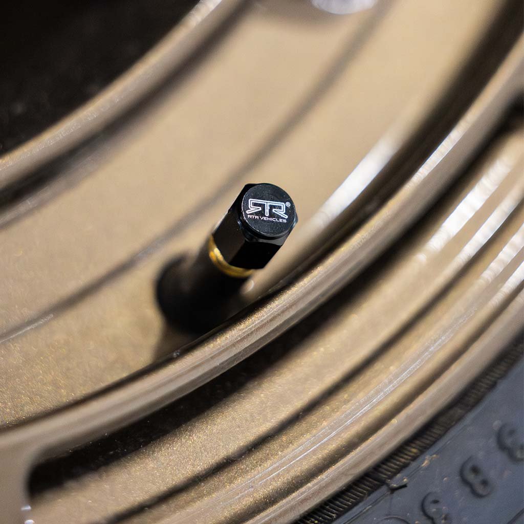 Close-up of RTR Valve Stem Caps, featuring black anodized aluminum with laser-etched RTR logo, showcasing a sleek design and universal fit for wheels.