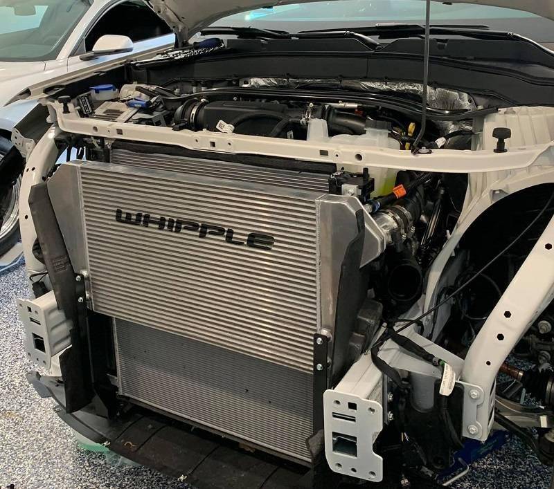 Whipple EcoBoost Mega Cooler (21+ Explorer ST) displayed with a large radiator and intercooler, surrounded by hoses and connectors, enhancing Ford Explorer's performance.