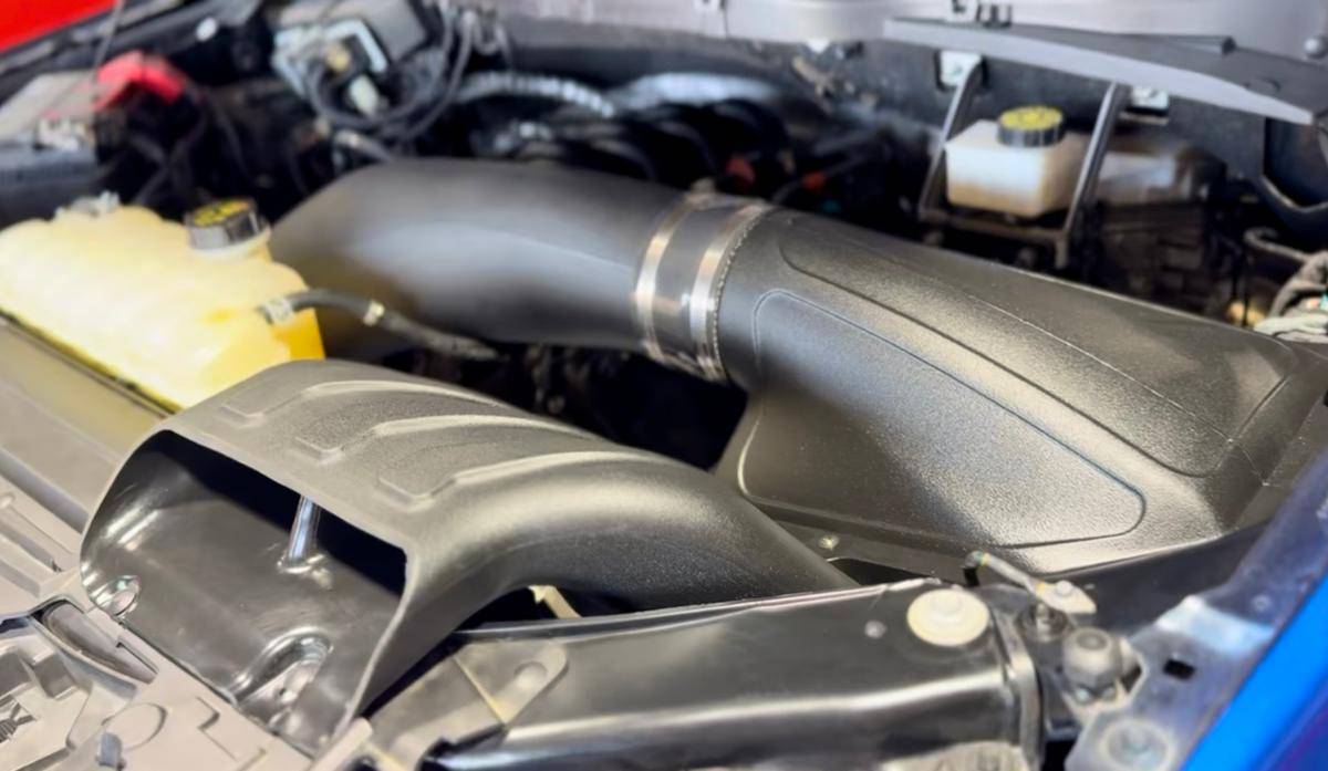 Whipple Superchargers Crusher Induction System in a modern vehicle engine bay, showcasing the large black air-intake snorkel and ducting, optimizing airflow and performance.