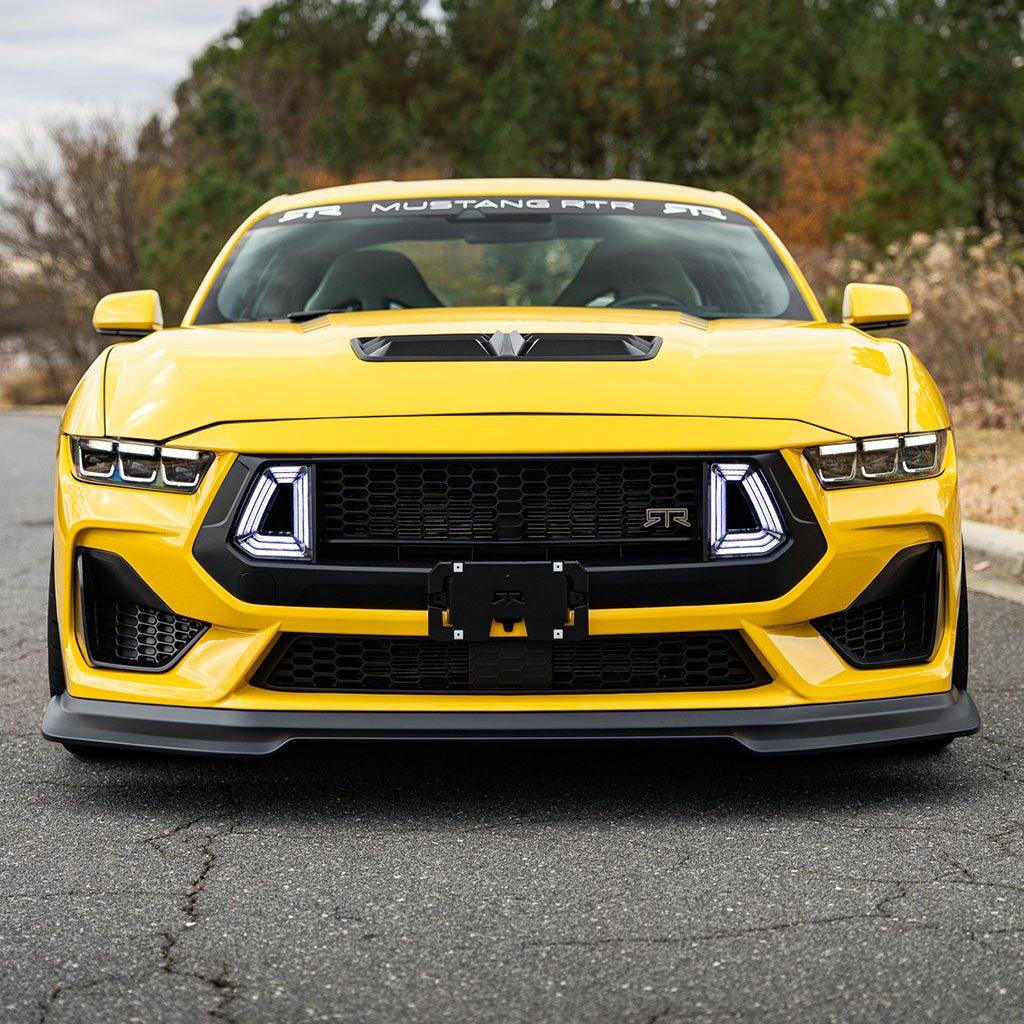 Front view of a yellow Mustang with RTR Front License Plate Bracket. Sleek design with RTR logo, ideal for Mustangs with RTR Upper Grille. Crafted from lightweight aluminum.